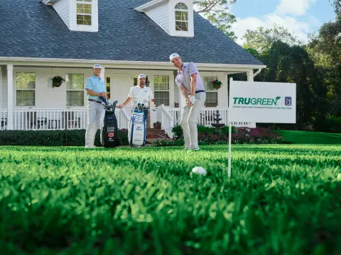 Two TruGreen lawn care specialists collaborating in front of a suburban home.